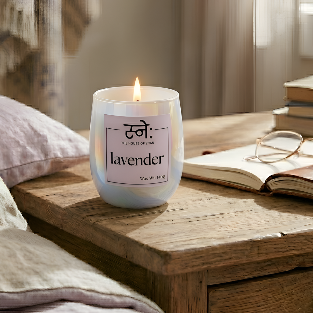 Lavender scented candle on a wooden surface with books and glasses in the background