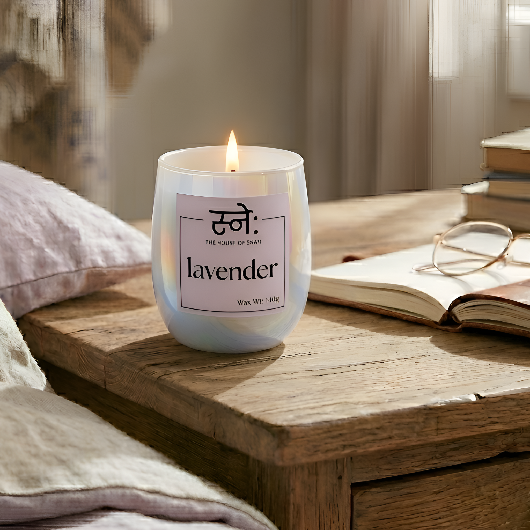 Lavender scented candle on a wooden surface with books and glasses in the background